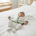 Hand knitted baby girl cardigan set in white and moss green featuring a frilly hem, hand embroidered flowers, matching hat, mittens and boots. Unique newborn to toddler outfit, perfect for baby showers, coming home outfits and special occasions.