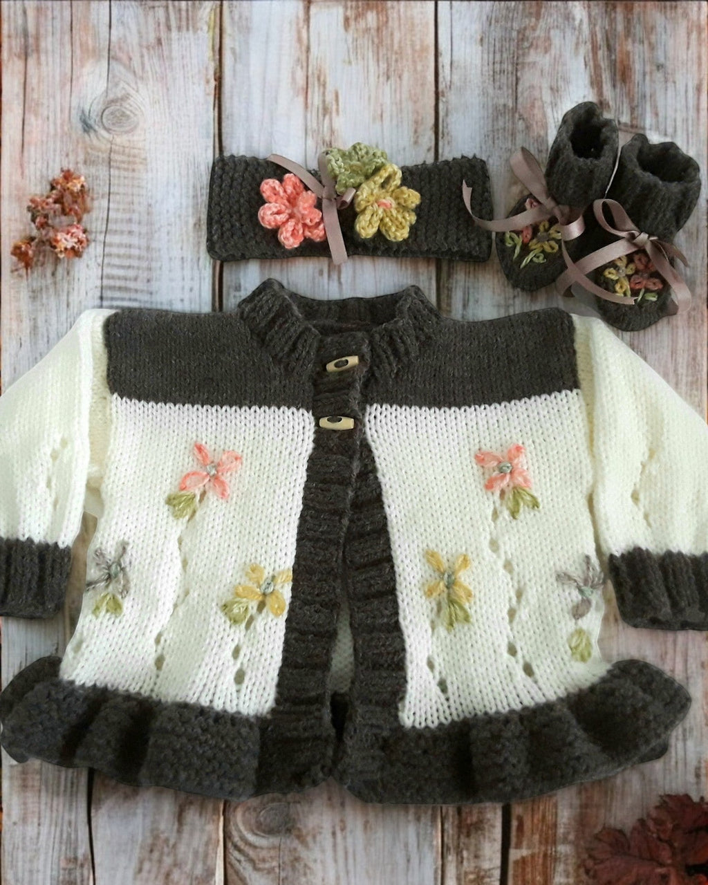 gemknits4kids baby girl wearing a brown and cream hand-knitted cardigan with floral details and matching headband & boots