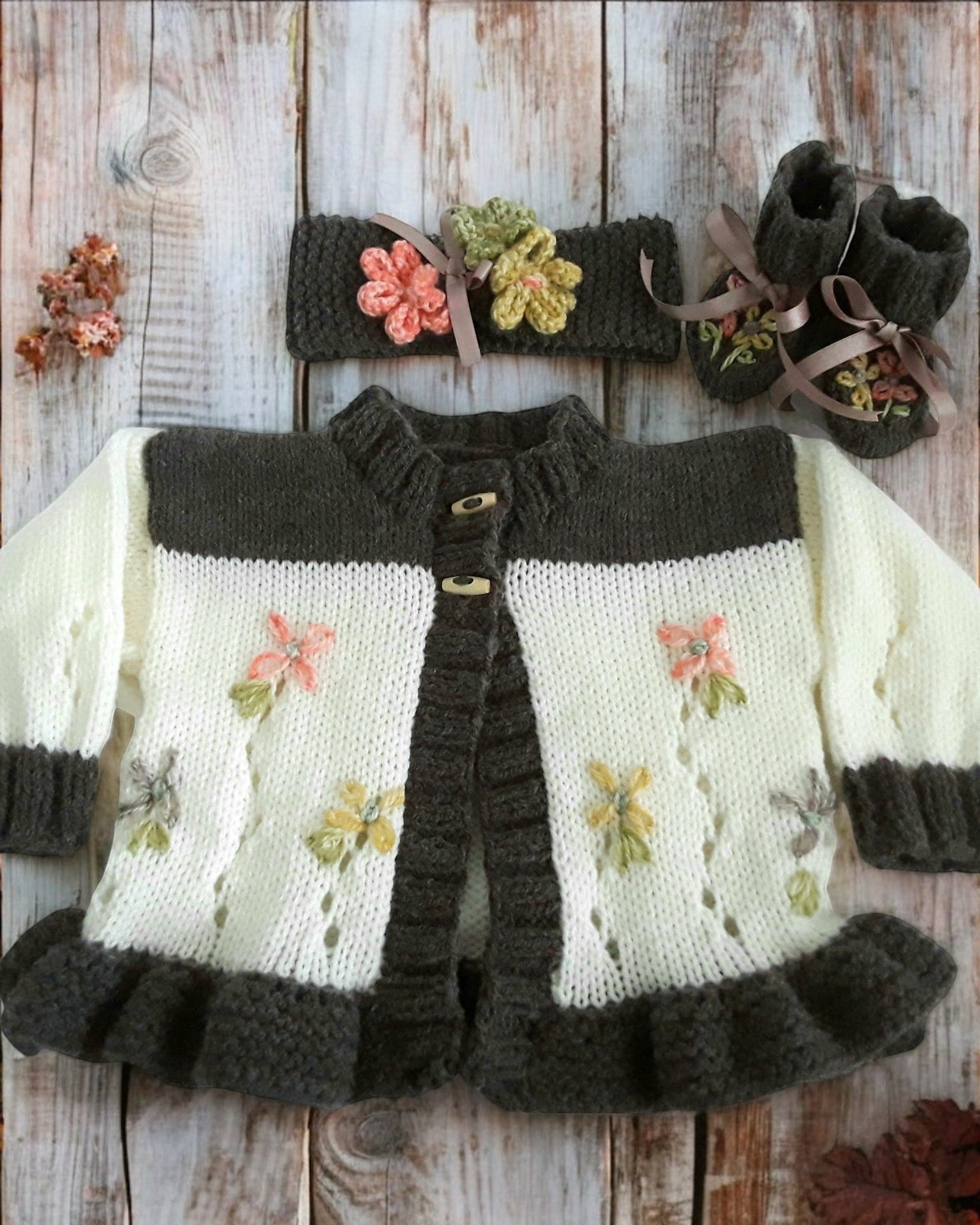 gemknits4kids baby girl wearing a brown and cream hand-knitted cardigan with floral details and matching headband & boots