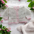 gemknits4kids baby girl sleeping in a white hand-knitted cardigan with delicate pastel pink trim hems