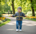 gemknits4kids baby boy wearing a charcoal and yellow striped hand-knitted cardigan and matching beanie in a park
