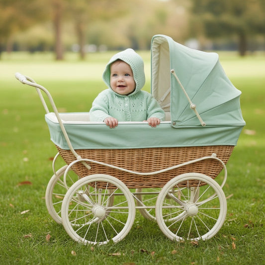 A baby wearing a soft mint green hand-knitted GemKnits4Kids hoodie with eyelet details, sitting in a vintage pram.