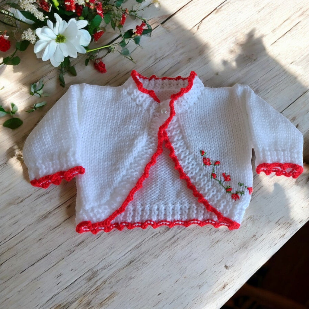 gemknits4kids white hand-knitted bolero cardigan withred embroidery worn by a toddler in a floral dress