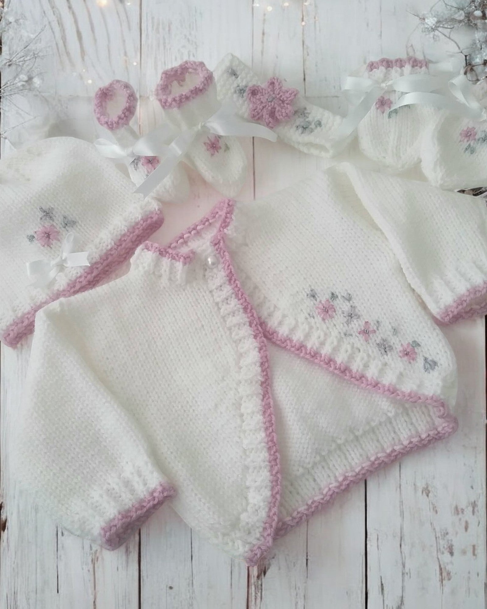 gemknits4kids white hand-knitted bolero cardigan with pink embroidery worn by a toddler in a floral dress