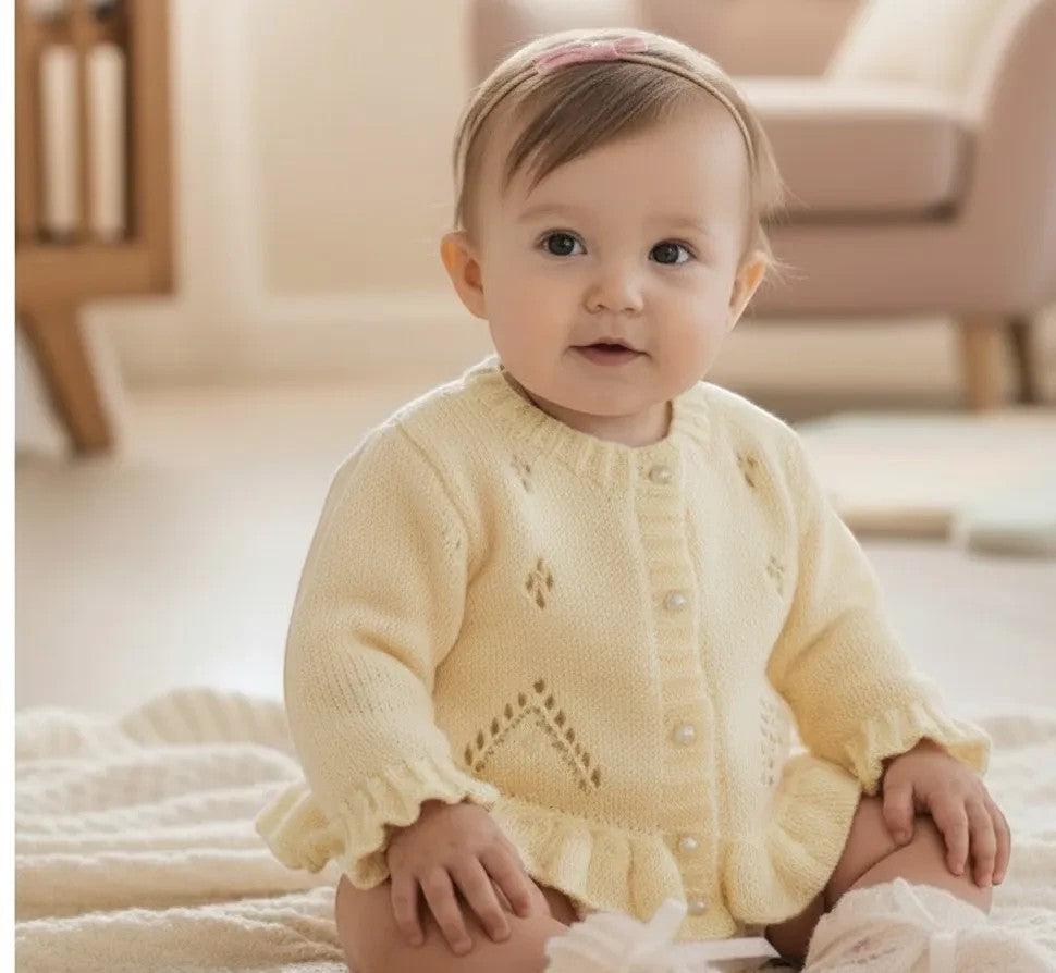gemknits4kids pale yellow hand-knitted girls cardigan with lace pattern, ruffle hem, and pearl buttons on a baby