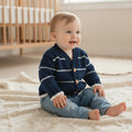 gemknits4kids baby boy wearing a Navy V-neck knitted cardigan with white stripes and wooden buttons over blue jeans