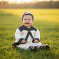 gemknits4kids baby girl wearing a brown and cream hand-knitted cardigan with floral details and matching headband & boots